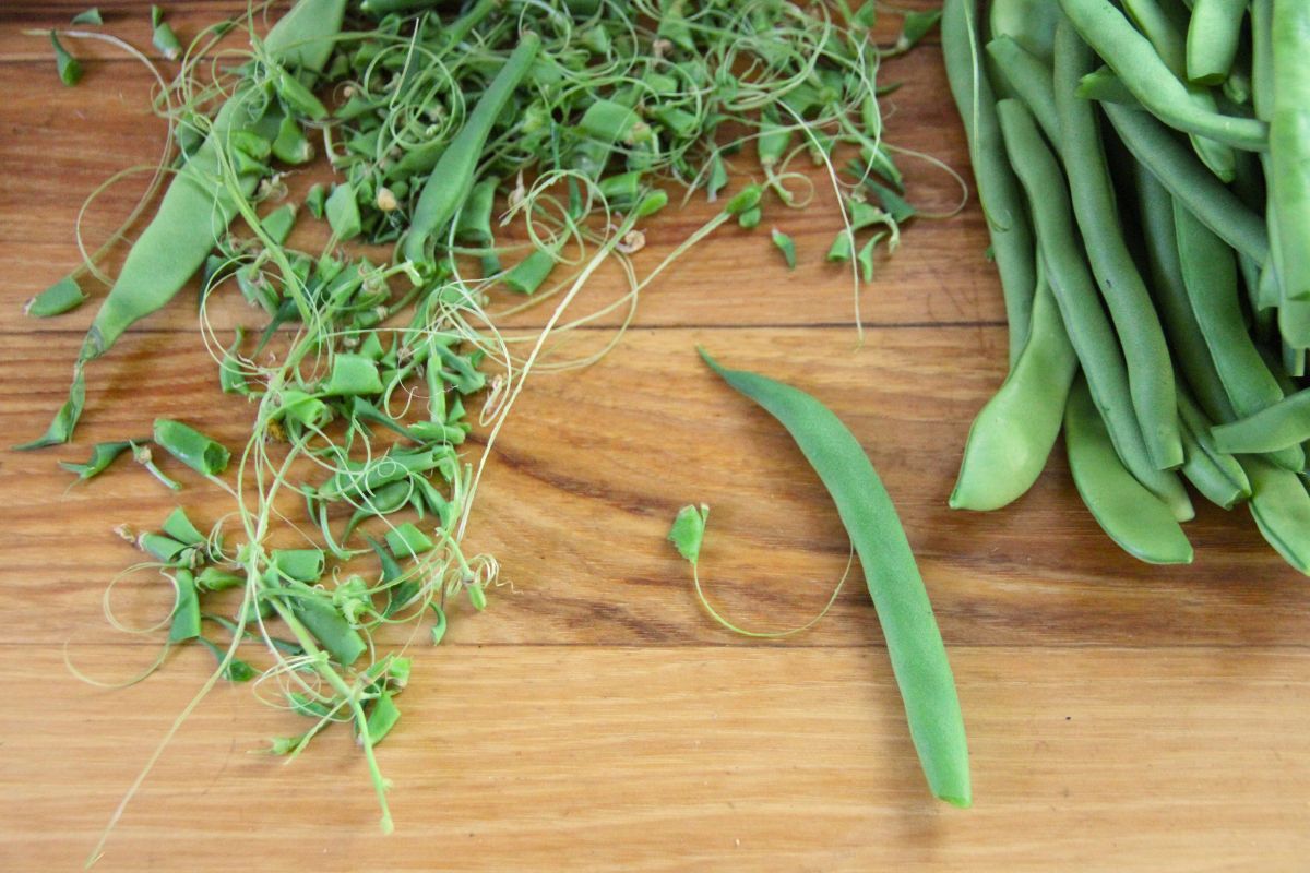 A pile of trimmed green beans and a smaller pile of trimmed ends.