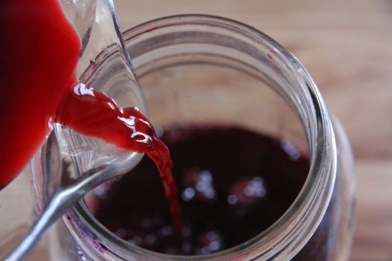 blackberry juice being poured into jar for fermenting