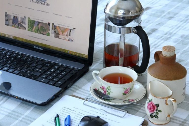 tea, a french press, laptop and clipboard