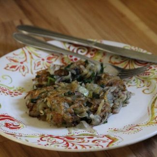 a plate, fork and knife with a crispy fried potato patty