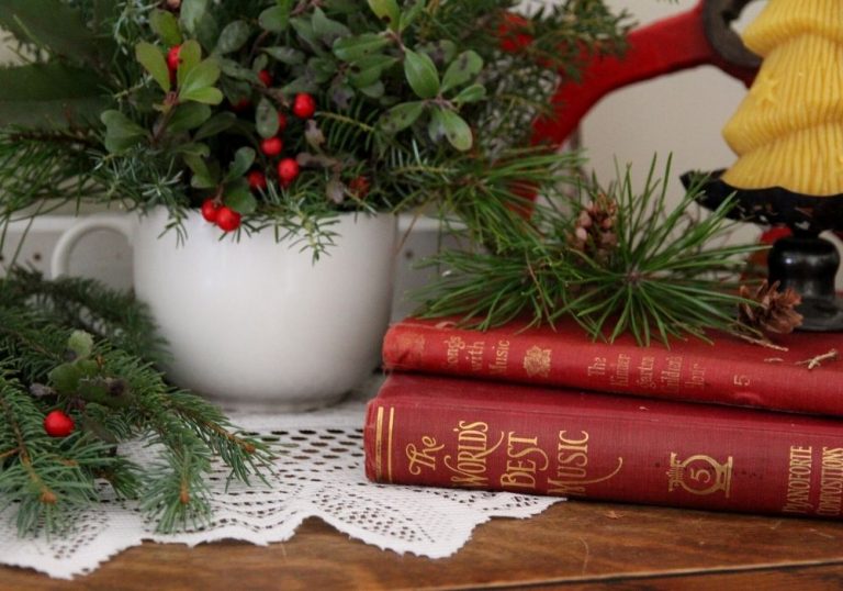 red books with gold letters laying on their side with a candle on top