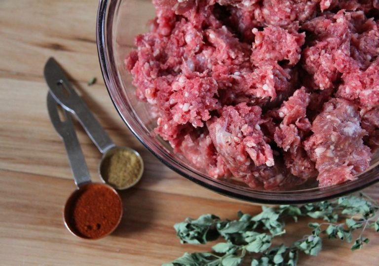 a bowl of fresh ground meat with spices on the side