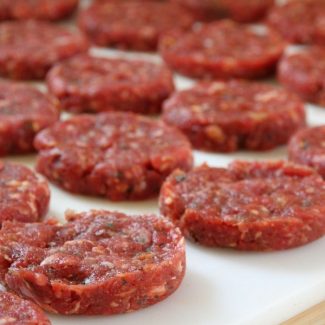 a cutting board filled with freshly formed sausage patties