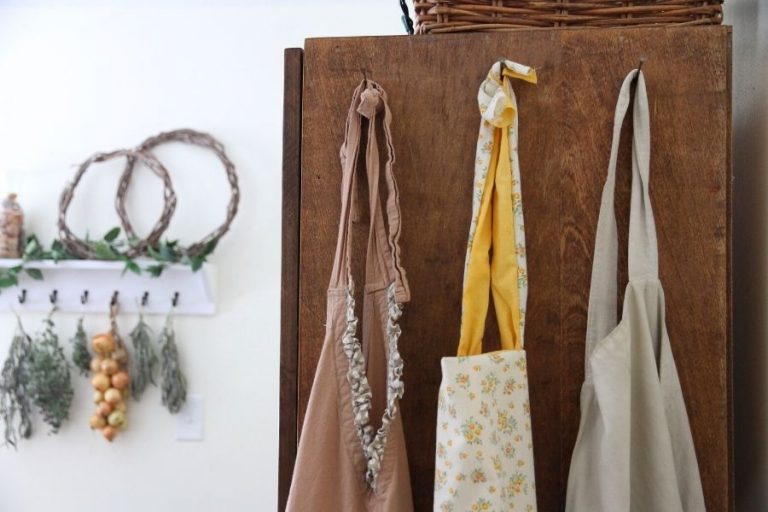 a row of aprons hanging on the side of a kitchen hutch