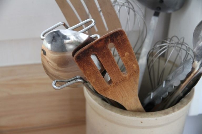 a small crock filled with stainless steel and wood cooking utensils