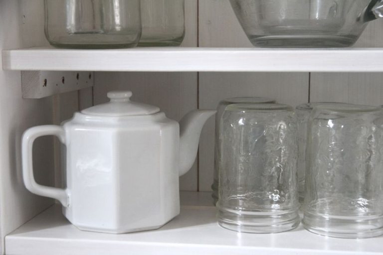 a white teapot sitting on an open kitchen shelf