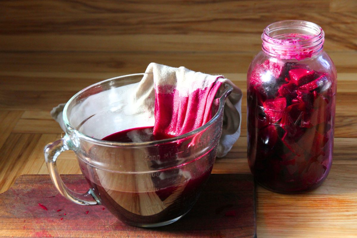 A bowl lined with a cotton cloth, filled with lacto-fermented beets and beet juice. 