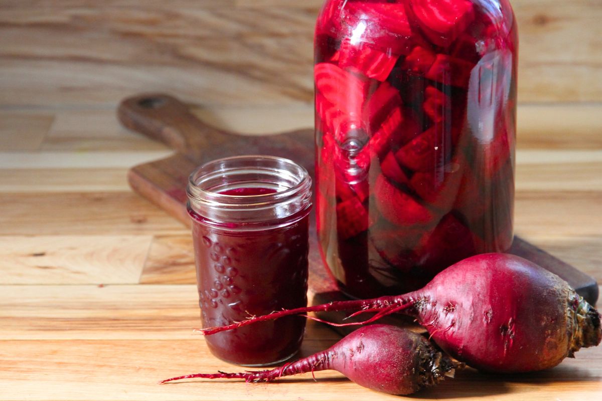 A jar of fermenting beet kvass, raw beets and a mason jar filled with fully fermented beet kvass. 