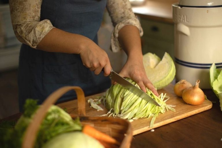 A woman chopping up cabbage on a cutting board