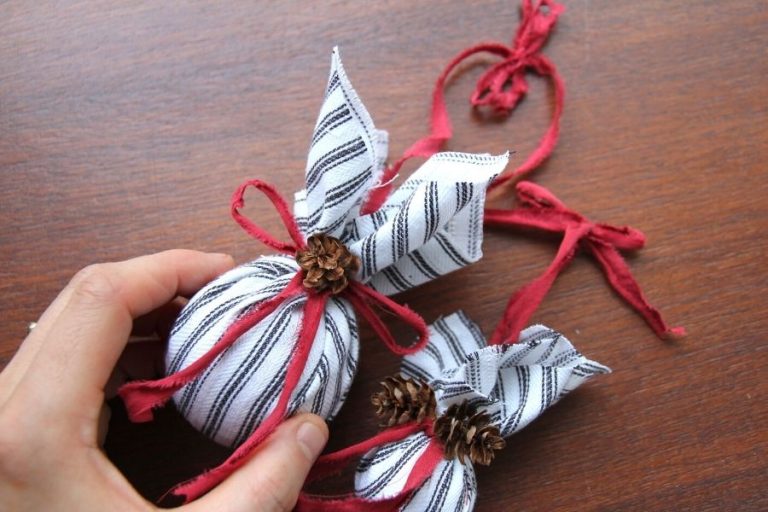 Farmhouse Christmas tree ornaments covered with ticking fabric and tied with a red bow