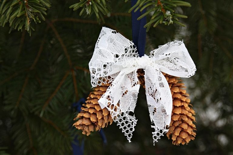 pine cone ornament tied up with a blue ribbon and decorated with a white lace bow