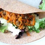 A soft tortilla filled with ground beef fajita, fresh greens and a side of herb dip.
