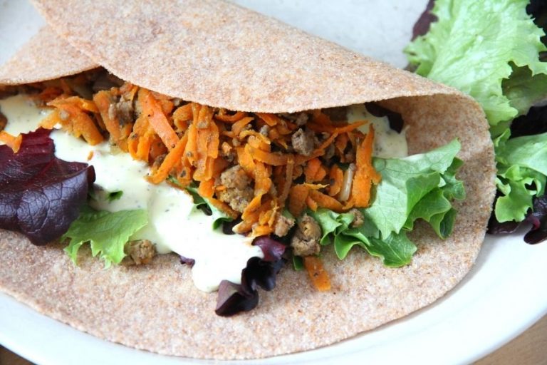 A soft tortilla filled with ground beef fajita, fresh greens and a side of herb dip.