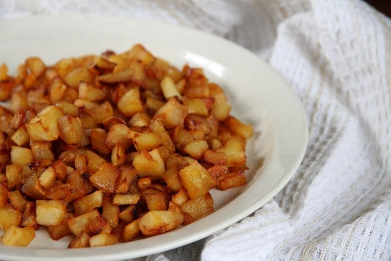a white plate filled with golden, roasted parsnips cubes