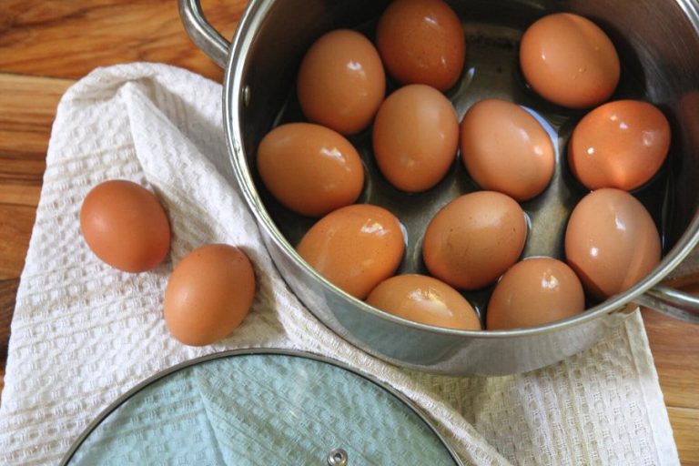 A dozen fresh hard boiled eggs in a stainless steel pot
