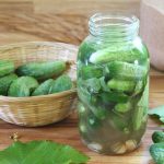 a jar stuffed with small pickling cucumbers and grape leaves, ready for fermenting