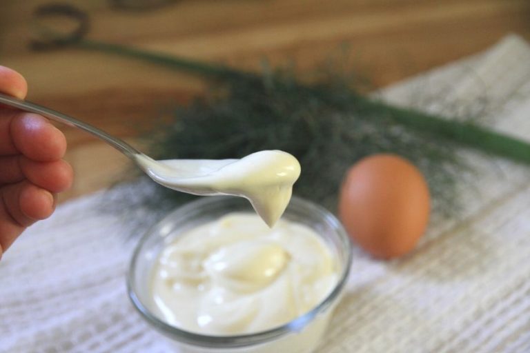 homemade mayonnaise sliding off a spoon into the bowl below