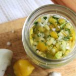 a jar of fermented salsa with yellow tomatoes on a wooden cutting board