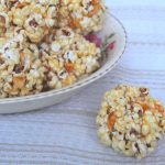 popcorn ball sitting beside a heaping bowl of honey popcorn balls