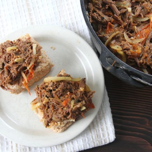 two homemade buns with pulled bear topping sitting on a plate next a black cast iron dutch oven