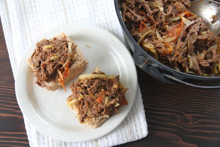 two homemade buns with pulled bear topping sitting on a plate next a black cast iron dutch oven