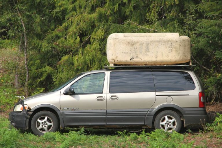 a giant blue bathtub unit on top of a tan minivan
