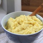 a blue bowl filled with fluffy yellow mashed potatoes