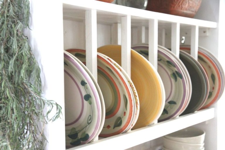 a row of colourful plates lined up in a white wood plate rack