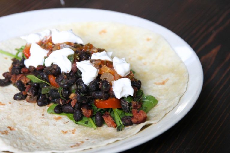 an open tortilla on a white plate revealing home canned black bean filling