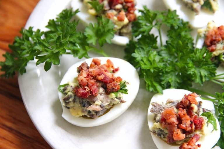 stuffed deviled eggs sitting on a white platter with parsley on the side