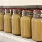 Jar of home canned applesauce lined up on a kitchen shelf