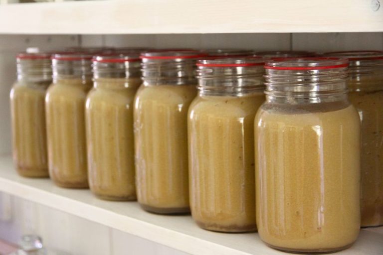 Jar of home canned applesauce lined up on a kitchen shelf