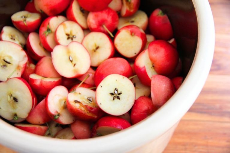 a 2-gallon stoneware crock filled with halved red crab apples