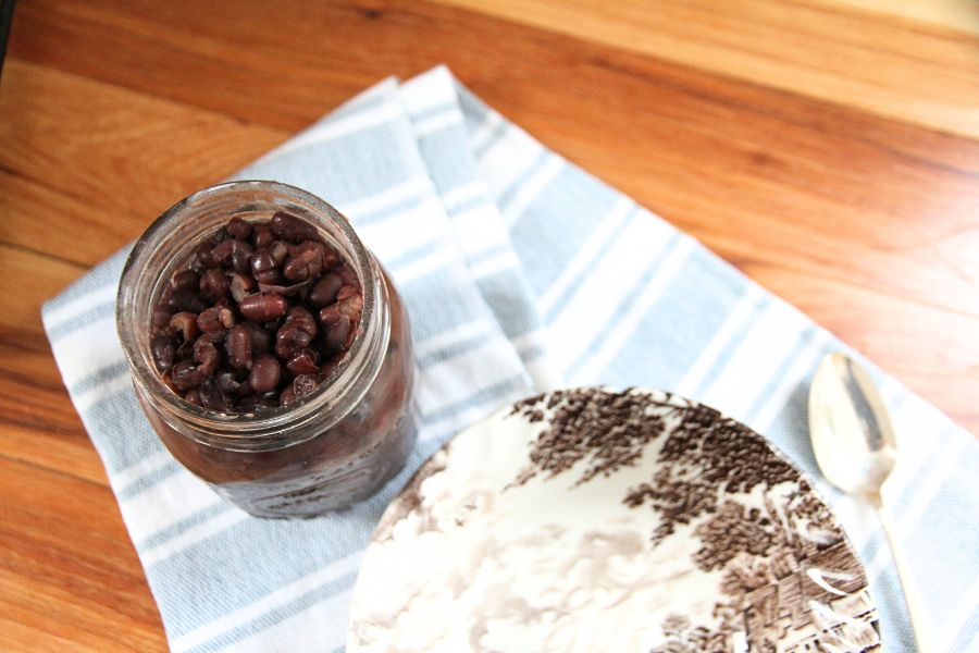 A jar of home canned beans sitting by a brown and white bowl