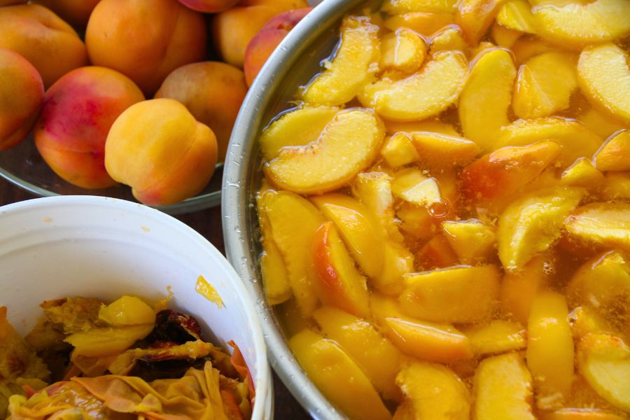 A large bowl of peeled and slices peaches, ready to be raw packed into canning jars.