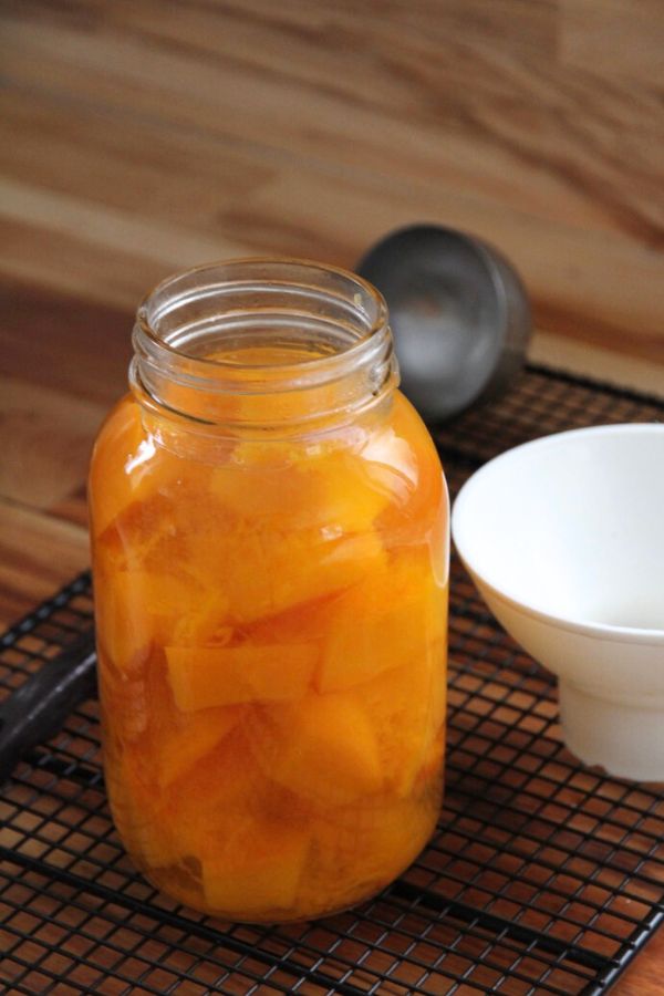 A quart jar filled with pumpkin and cooking liquid, ready for a canning lid and band.