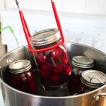A water bath canner filled with jars of home canned sweet cherries.