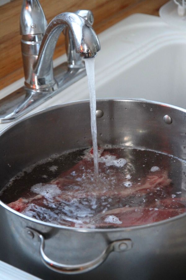 Deer bones in a large stock pot with tap water being added in.