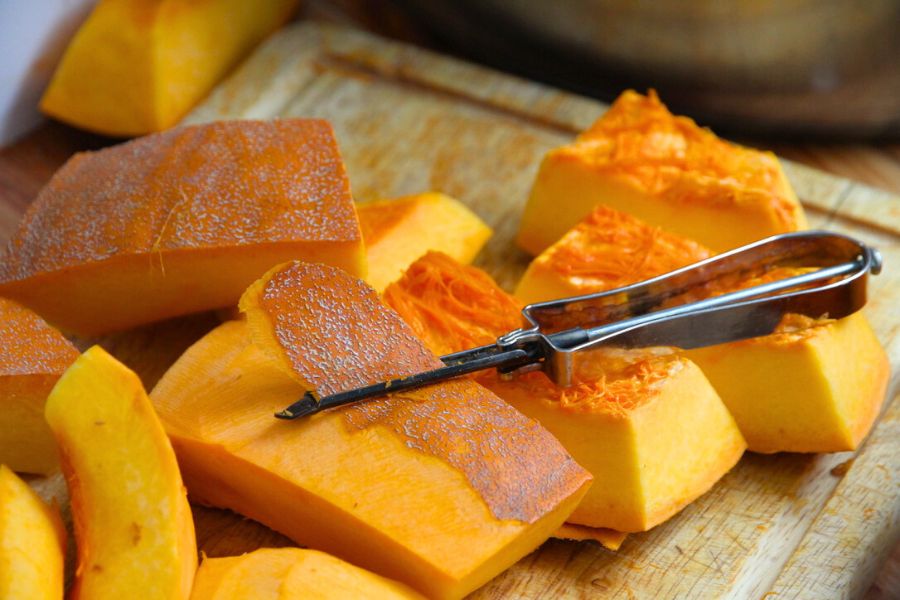 Slices of pumpkin being peeled with a vegetable peeler.