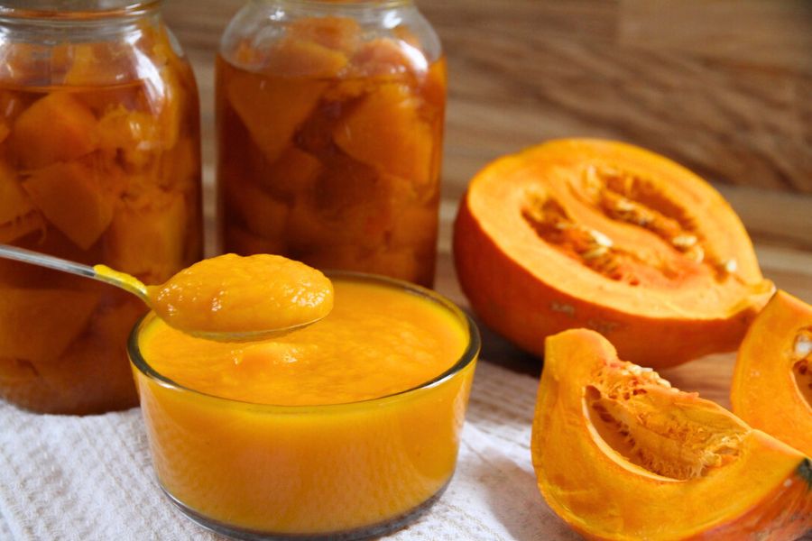 A bowl of homemade pumpkin puree in front of home canned jars of pumpkin cubes.