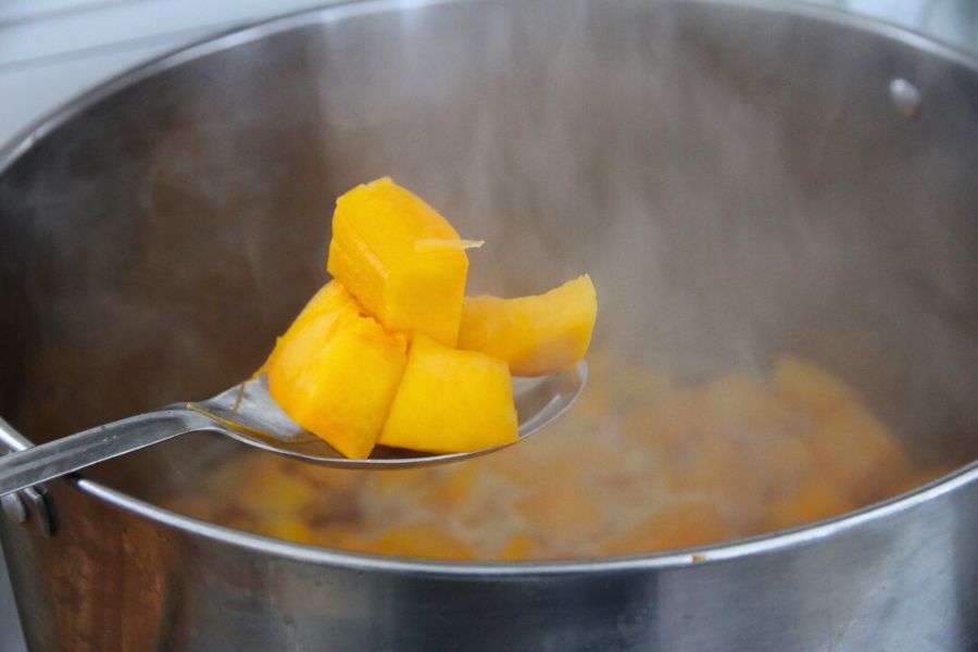 Pumpkin chunks being heated in boiling water before ladling into canning jars.