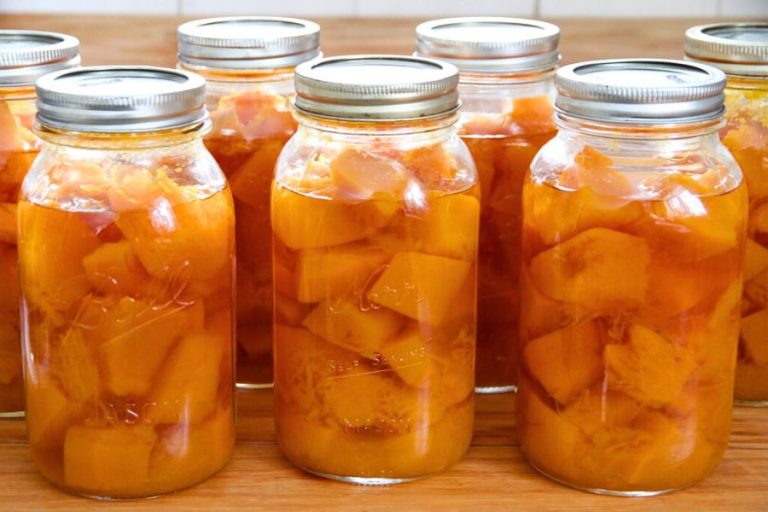 Jars of home-canned pumpkin sitting on a wooden kitchen counter.