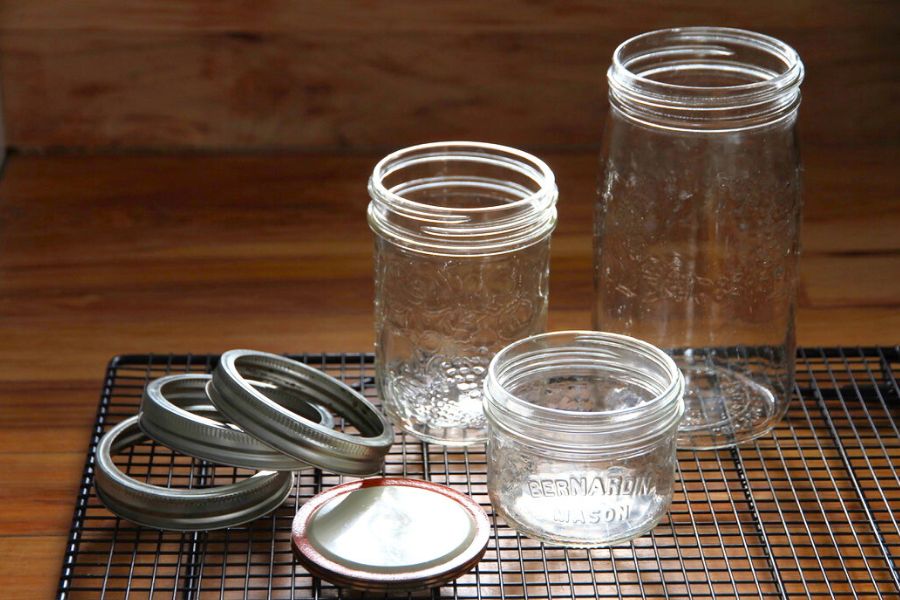 Three wide mouth canning jars on the kitchen counter that are half pint, pint and quart-size.