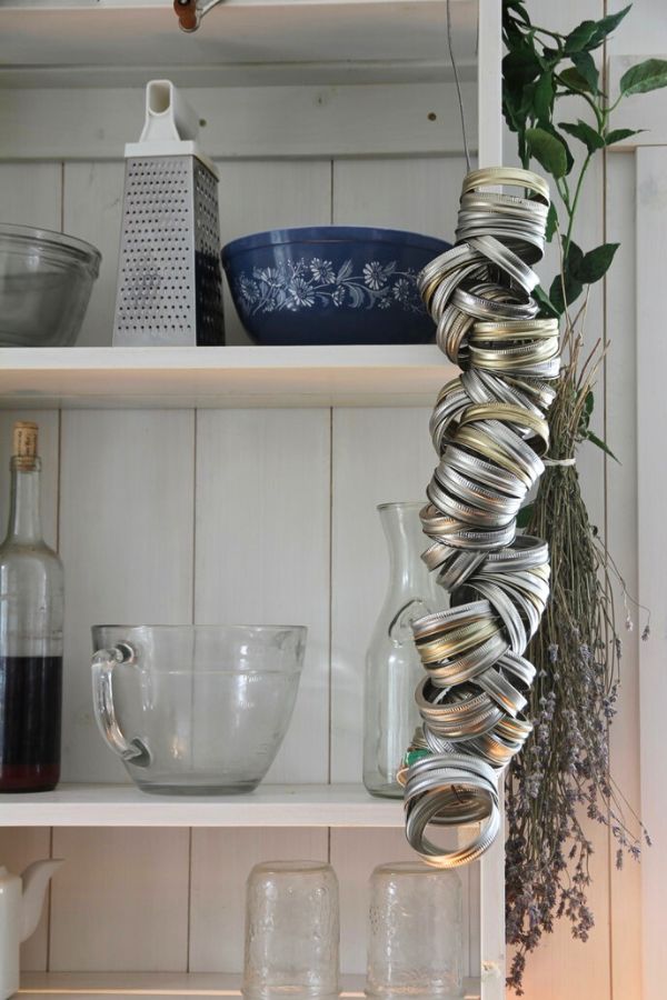 A string of canning rings hanging from an open kitchen shelf on canning day.