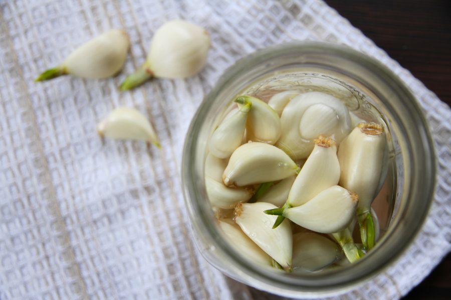 A jar of peeled whole garlic cloves topped with salt water.