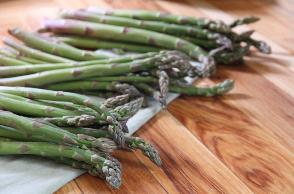 Bundles of fresh asparagus laid out on the kitchen counter