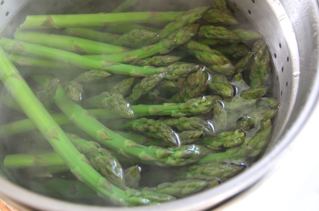 Fresh asparagus blanching in a large pot of hot water.