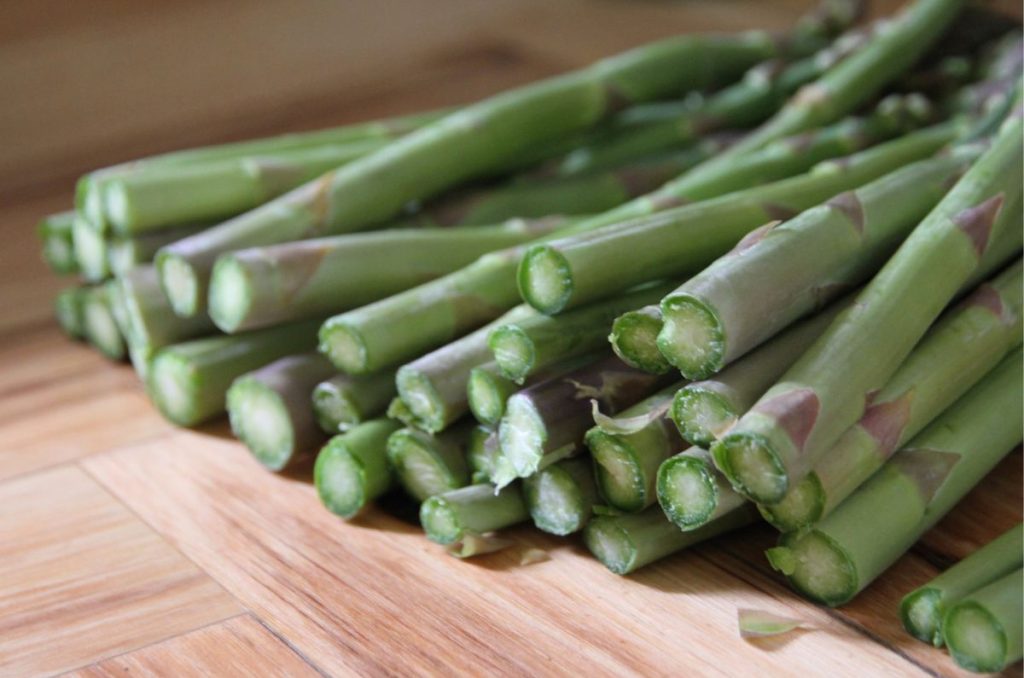 A large bundle of asparagus with freshly cut ends that are moist and tender.