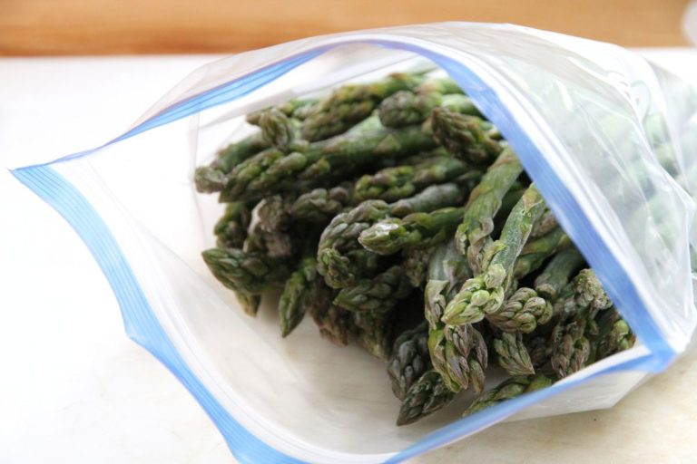 A plastic bag filled with frozen asparagus stalks.