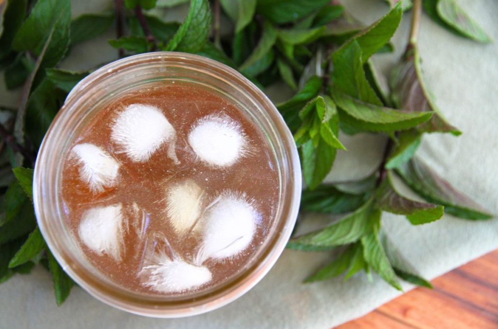 A jar of refreshing chilled mint tea with ice cubes floating on top.